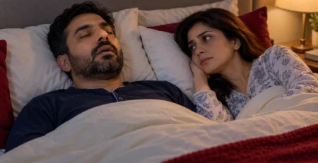 Man asleep beside his awake partner, illustrating how snoring can affect shared sleep.